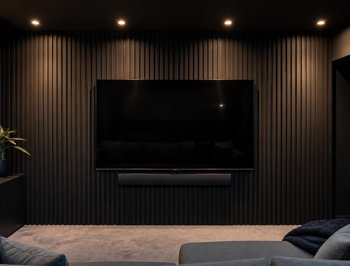 Dark charcoal acoustic slat panel TV wall with a mounted TV and soundbar below